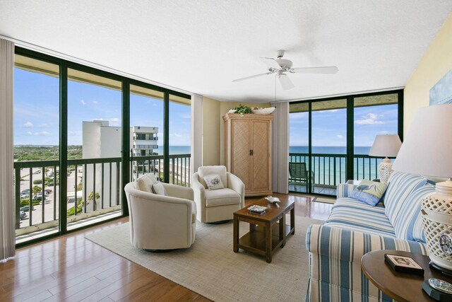 living room featuring floor to ceiling windows, a water view, ceiling fan, and hardwood / wood-style floors