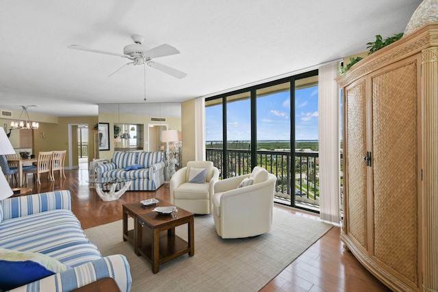 living room with expansive windows, hardwood / wood-style flooring, and ceiling fan with notable chandelier