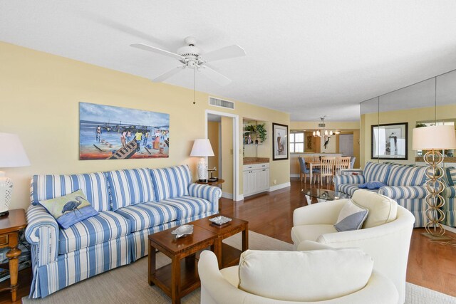 living room with ceiling fan with notable chandelier and hardwood / wood-style flooring