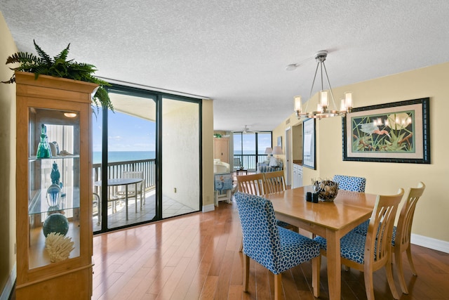 dining area featuring floor to ceiling windows, a water view, hardwood / wood-style flooring, and plenty of natural light