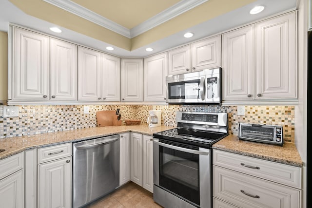 kitchen featuring stainless steel appliances, crown molding, tasteful backsplash, and white cabinetry