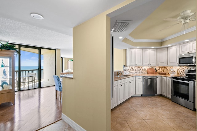 kitchen featuring stainless steel appliances, a water view, ceiling fan, and white cabinetry