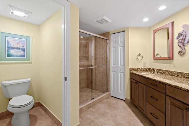 bathroom with vanity, a shower with shower door, and toilet