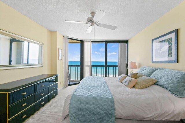 bedroom with a water view, ceiling fan, access to exterior, and a textured ceiling