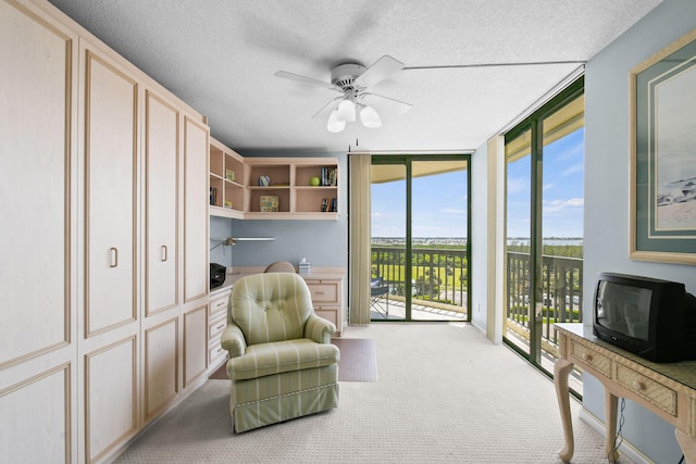 sitting room featuring a wall of windows, light carpet, ceiling fan, and plenty of natural light