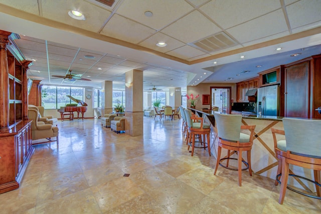 kitchen featuring a healthy amount of sunlight, stainless steel fridge, ceiling fan, and a drop ceiling