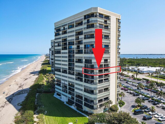 view of building exterior featuring a water view and a beach view