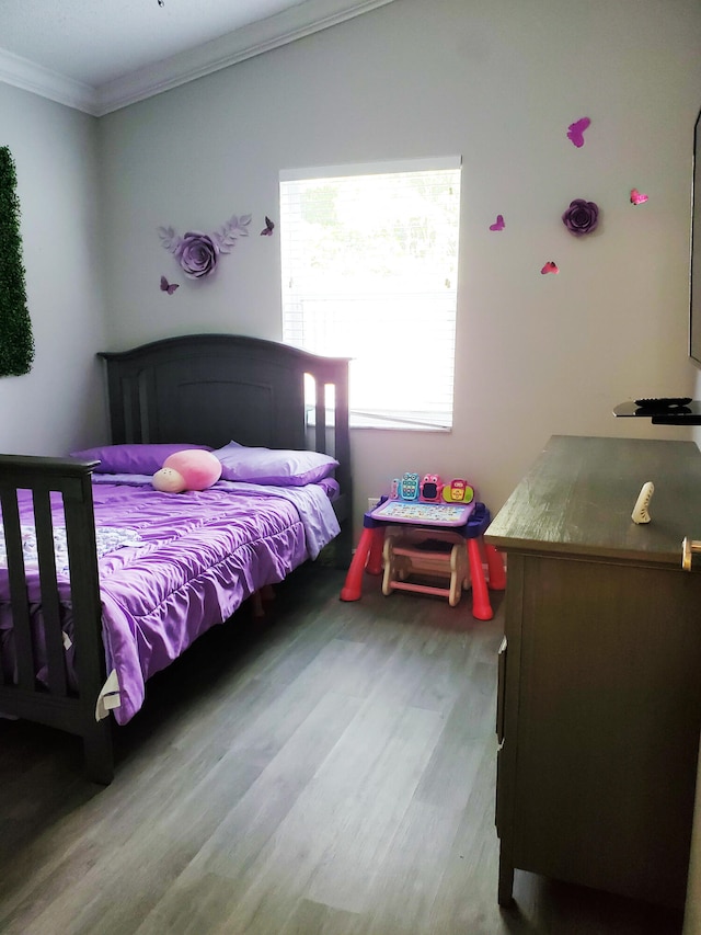 bedroom with ornamental molding and wood-type flooring