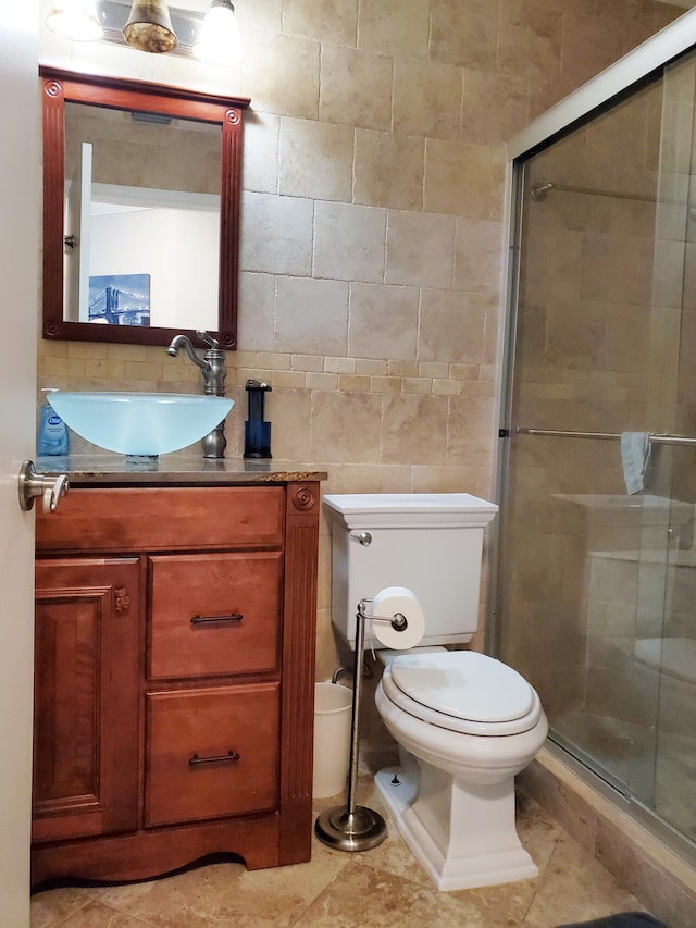 bathroom featuring walk in shower, toilet, tile patterned floors, tile walls, and vanity