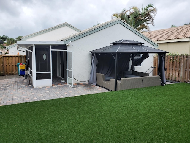 rear view of house featuring a lawn, a gazebo, a sunroom, and a patio area