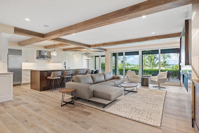 living room with sink, beamed ceiling, and light hardwood / wood-style floors