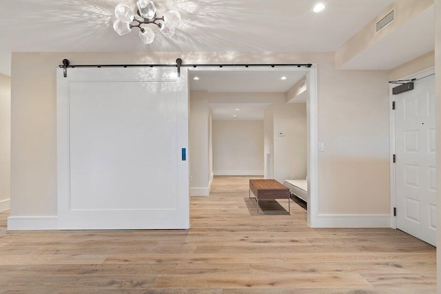 corridor with light wood-type flooring and a barn door