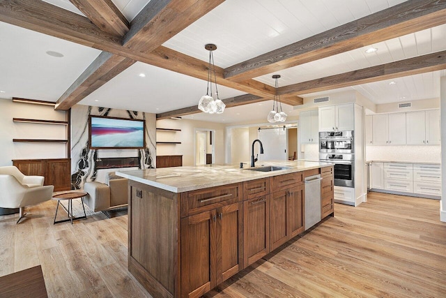 kitchen with white cabinets, beam ceiling, a spacious island, and light stone countertops