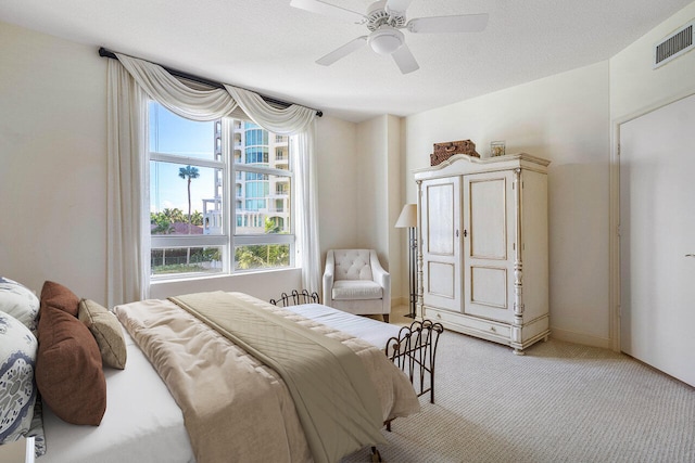 carpeted bedroom with ceiling fan and a textured ceiling