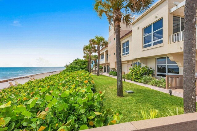 surrounding community with a yard, a water view, and a view of the beach