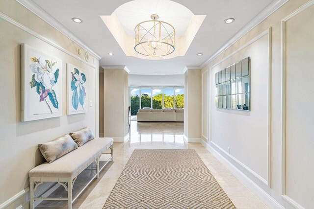 hall featuring a raised ceiling, crown molding, and a notable chandelier