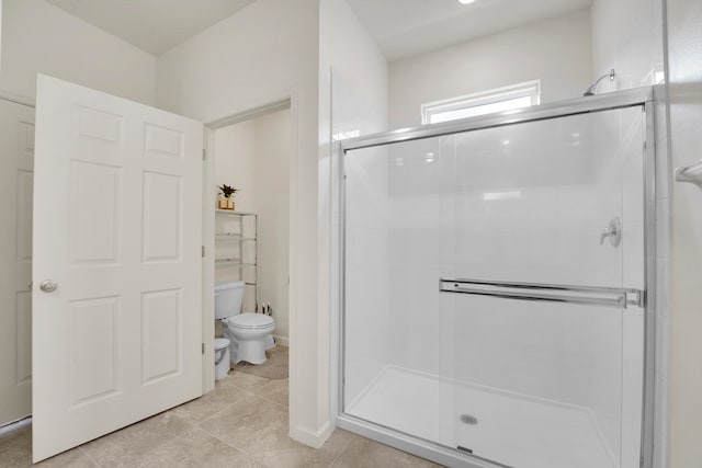 bathroom featuring tile patterned flooring, a shower with shower door, and toilet