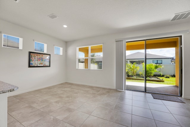 empty room featuring a textured ceiling and light tile patterned floors