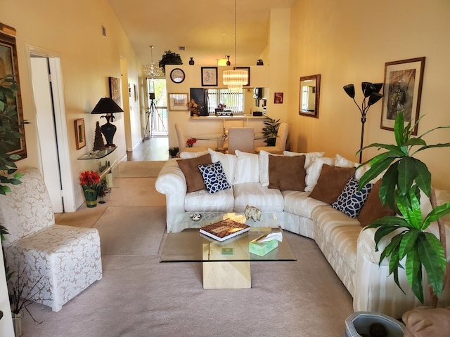 carpeted living room featuring an inviting chandelier and high vaulted ceiling