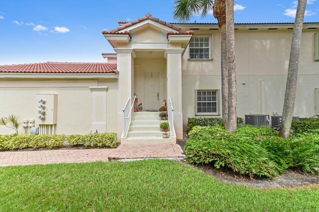 view of front of home with central air condition unit and a front lawn