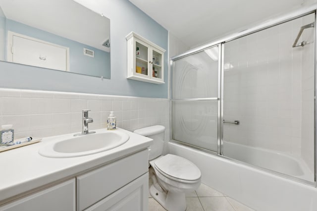 full bathroom featuring bath / shower combo with glass door, tile walls, toilet, vanity, and tile patterned floors