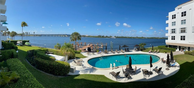 view of pool featuring a water view, a yard, and a patio