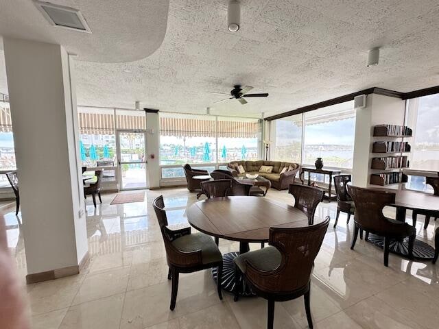 tiled dining room featuring expansive windows, a textured ceiling, ceiling fan, and a wealth of natural light