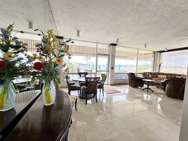 tiled dining space featuring a wall of windows and a textured ceiling