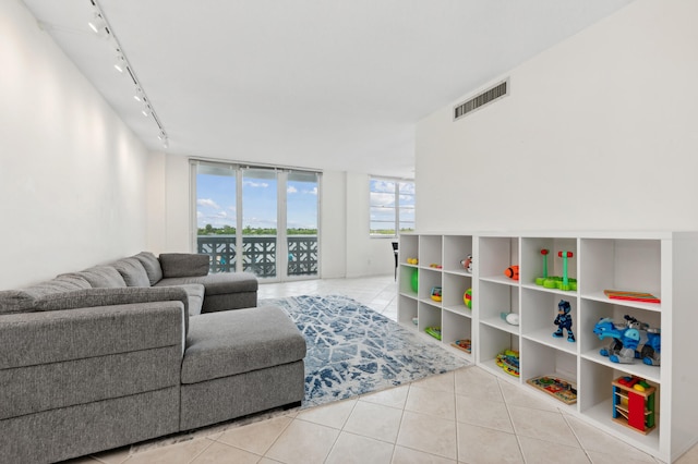 living room with track lighting, light tile patterned floors, and a wall of windows