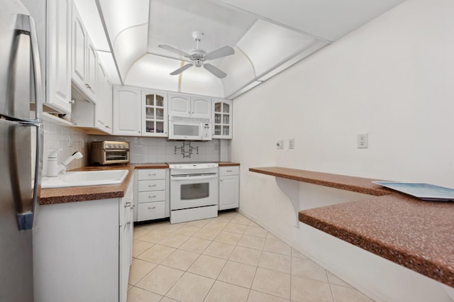 kitchen featuring decorative backsplash, white cabinets, sink, and white appliances