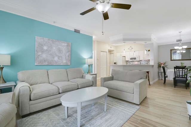 living room with ceiling fan with notable chandelier, light hardwood / wood-style floors, and ornamental molding