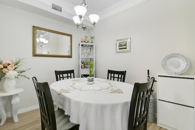 dining space with light wood-type flooring, ornamental molding, and a notable chandelier