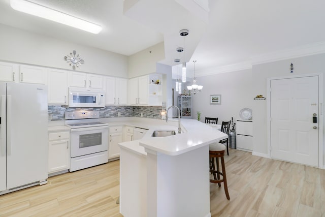 kitchen with white appliances, kitchen peninsula, pendant lighting, a kitchen bar, and sink