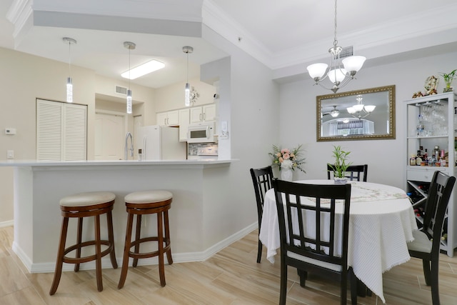 dining space featuring light wood-type flooring, crown molding, an inviting chandelier, and sink