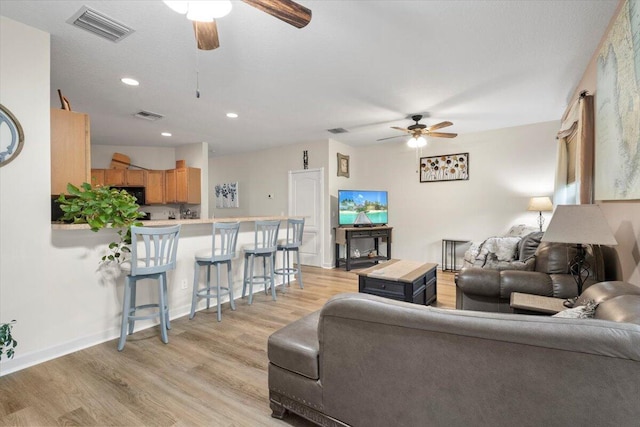 living room featuring light hardwood / wood-style flooring and ceiling fan