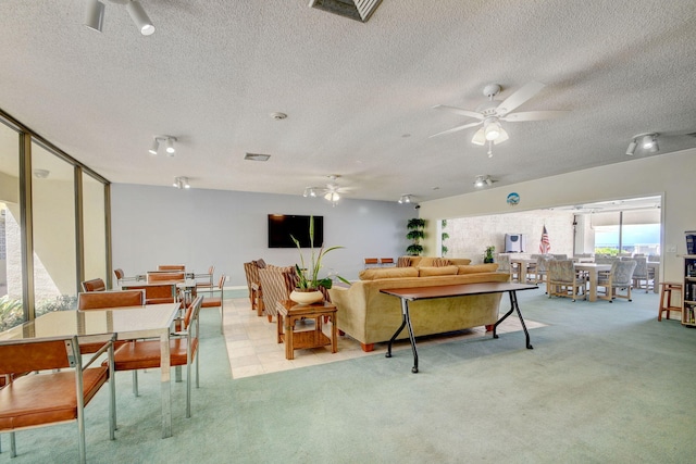 living room with a textured ceiling, light colored carpet, and ceiling fan