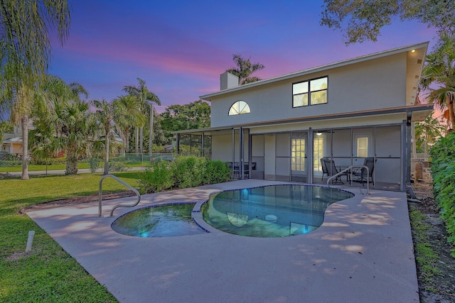 back house at dusk with a pool with hot tub, a patio area, and a yard