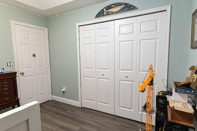 bedroom featuring a closet, dark hardwood / wood-style floors, and a textured ceiling