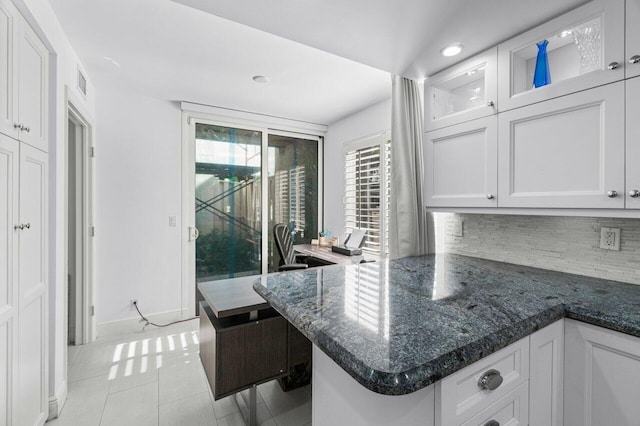 kitchen with white cabinets, kitchen peninsula, backsplash, and light tile patterned floors