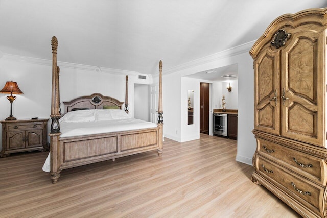 bedroom featuring wine cooler, ornamental molding, light hardwood / wood-style flooring, and ensuite bathroom