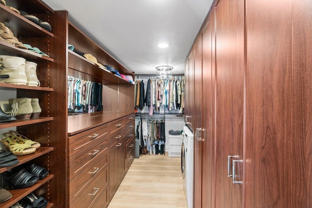 walk in closet with light hardwood / wood-style flooring and washing machine and dryer