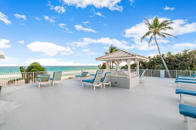 view of patio with a gazebo, a water view, and a view of the beach