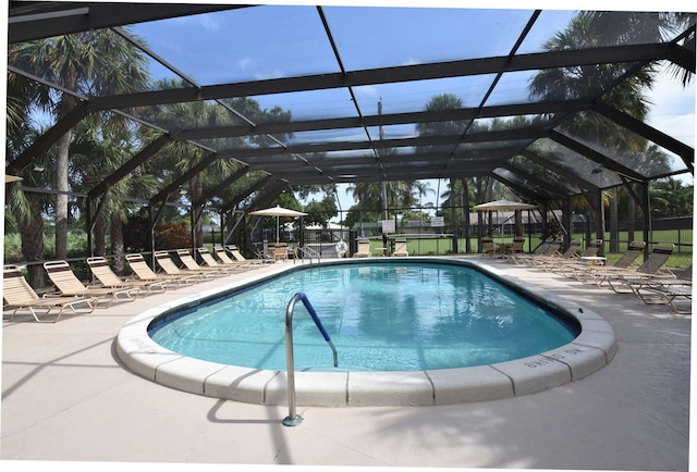 view of pool with glass enclosure and a patio area