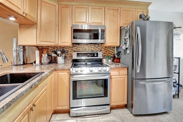 kitchen featuring stainless steel appliances, light brown cabinets, backsplash, light tile patterned flooring, and sink