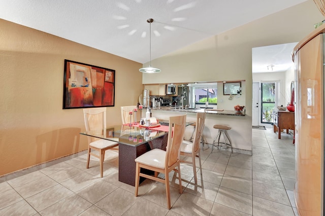 tiled dining room featuring vaulted ceiling