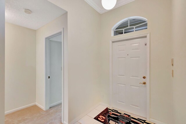 kitchen featuring dishwasher, sink, light tile patterned floors, crown molding, and white cabinets