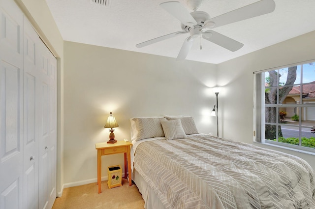 bedroom featuring ceiling fan, light carpet, and a closet