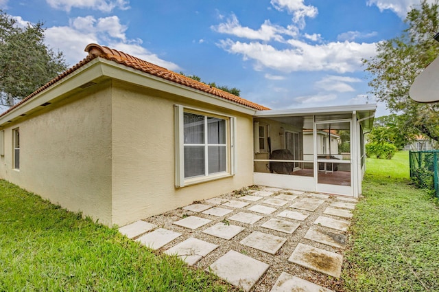 rear view of property featuring a patio area, a sunroom, and a yard