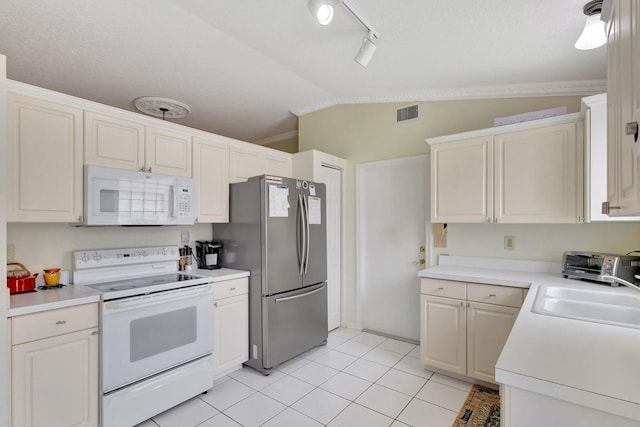 kitchen with white appliances, sink, vaulted ceiling, light tile patterned floors, and a textured ceiling