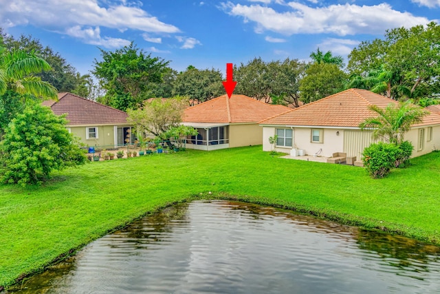 back of property with a lawn and a water view